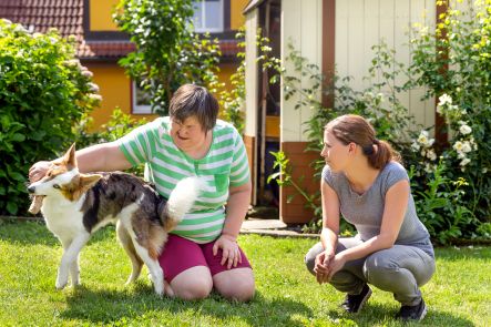Geistig behinderte Frau mit Betreuerin und Hund im Garten